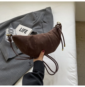 Detail of dark brown matte crescent bag featuring decorative stitching and knotted strap