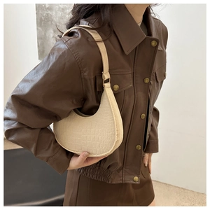 Model wearing a retro crescent shoulder bag with cream crocodile texture and gold buckle