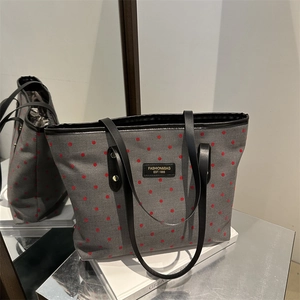 Chic grey canvas tote bag with red polka dots and black leather handles in a mirrored view