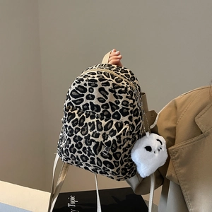 Mini zaino leopardato con ciondolo di peluche e cerniere in metallo in vista a mano