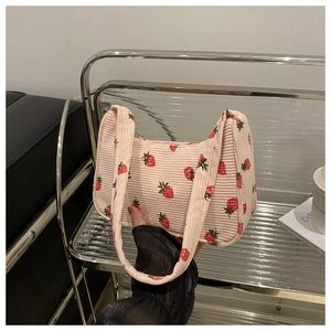 Détail d'un sac porté épaule en velours rose avec imprimé fraises sur support