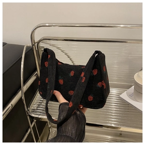 Détail d'un sac à bandoulière en velours noir avec broderies de fraises et texture plissée