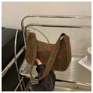 Gros plan détaillé du sac bandoulière en velours côtelé marron avec broderie fraise