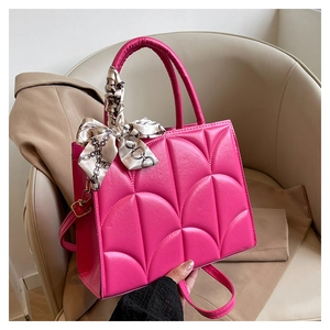 Détail du sac cabas rouge rose avec motif matelassé et foulard en soie décoratif sur l'anse