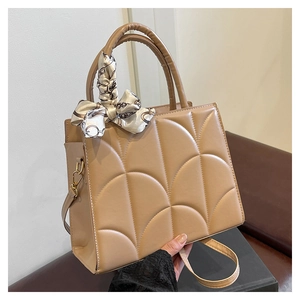 Détail d'un sac à main beige matelassé avec poignée en foulard de soie et ferrures dorées