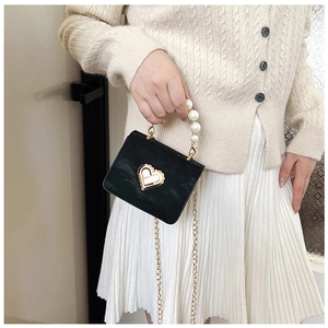 Detailed macro view of black mini crossbody bag with pearl handle and golden heart lock