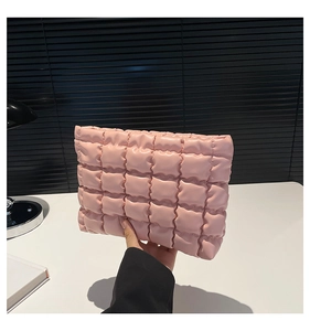 Dettaglio di una pochette rosa trapuntata a quadri con consistenza morbida e imbottita