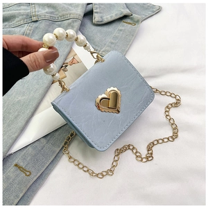 Detail of light blue textured mini bag with heart lock, pearl handle and gold chain strap
