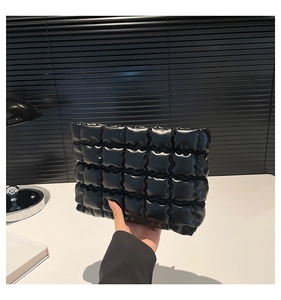 Dettaglio pochette nera trapuntata con finitura opaca e design moderno a pieghe morbide