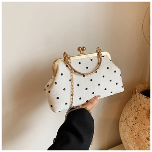 Close-up of retro polka dot handbag featuring gold metal frame and bead clasp closure