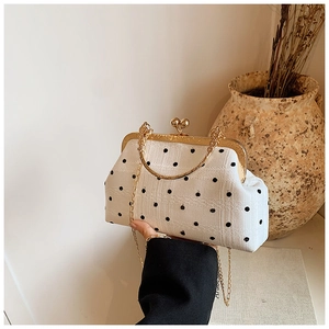 Close-up of retro black polka dot kiss-lock bag with gold chain and handle details