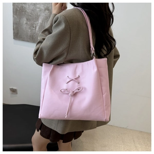 Detail view of pink nylon tote bag featuring bow tie strap and metallic ring hardware