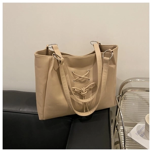 Detail of apricot tote bag with drawstring lace-up design and silver rings on faux leather
