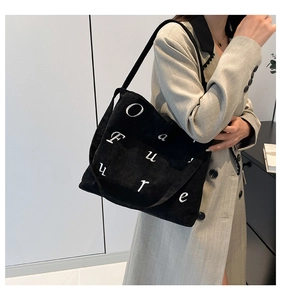Détail du sac cabas en velours côtelé noir avec broderie de lettres blanches sur le côté