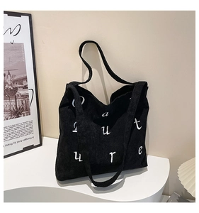 Détail du sac cabas en velours côtelé noir avec texture côtelée et broderie de lettres