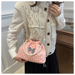 Detailed view of pink polka dot drawstring bucket bag with pearl handle and metal butterfly