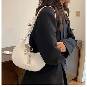 Detail of white glossy crescent shoulder bag featuring silver pearl bow charm
