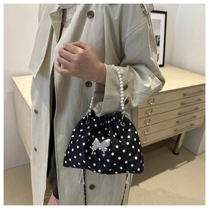Lifestyle shot of polka dot bucket bag with metal butterfly and pearl handle detail