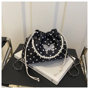 Detail of beaded handle and silver butterfly decor on black polka dot bucket bag