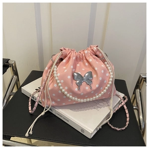 Detailed view of pink polka dot bucket bag with pearl handle and butterfly charm