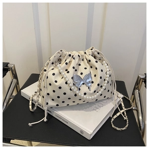 Detailed shot of cream polka dot bucket bag with pearl chain and butterfly metal charm