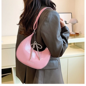 Detailed macro view of pink patent leather hobo bag with Fashion logo and metallic bow