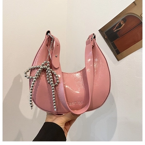 Detail of bright pink patent leather crescent bag with decorative silver beaded bow