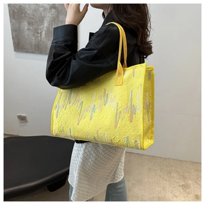 Détail du sac cabas jaune avec gaufrage en E discret et broderie ondulée colorée
