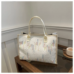 Gros plan du sac cabas texturé avec broderie rayée colorée et poignées tissées