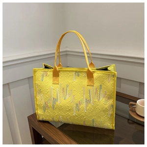 Détail du sac cabas jaune avec texture matelassée en losange et broderies ondulées