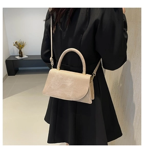 Detail of minimalist beige handbag showing fine suede texture and sleek metal clasp