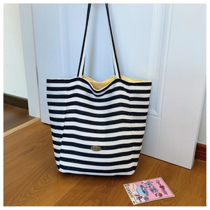 Detail of striped canvas tote bag with handmade metal badge and yellow lining