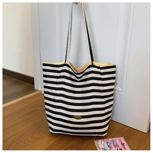 Close-up of striped canvas tote with handmade metal logo and bright yellow lining