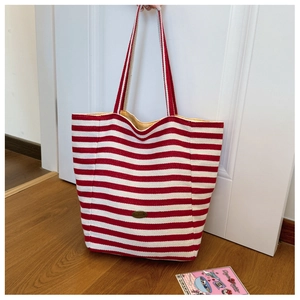 Detail of red and white striped canvas tote bag showing the Handmade oval logo patch