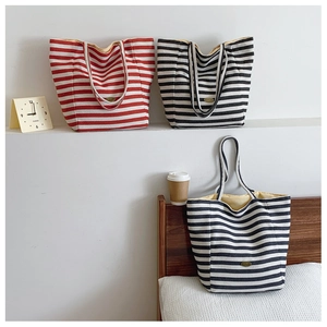 Multiple striped canvas tote bags in red and black displayed in a cozy indoor setting
