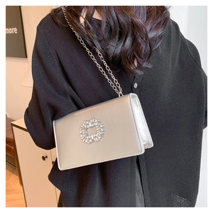 Detail of silver rhinestone square bag with chain strap shown on a black sweater