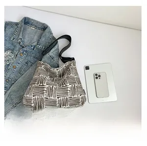 Détail du sac fourre-tout en toile à carreaux avec texture tissée et large bandoulière noire