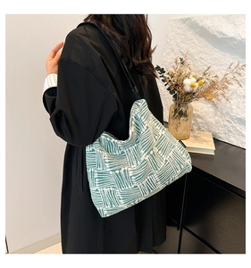 Détail de la texture tissée verte et beige d'un grand sac cabas porté à l'épaule