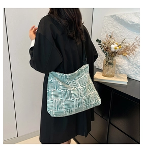 Détail du sac cabas tissé vert et blanc avec large bandoulière réglable porté par le mannequin