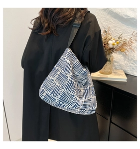 Détail du sac cabas en toile à rayures bleues porté à l'épaule par le modèle