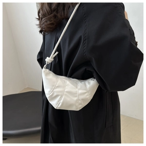 Détail de sac croissant blanc avec texture plissée et nœud élégant sur la bandoulière
