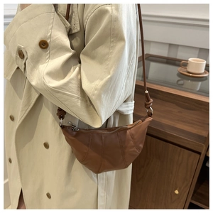 Detail of the brown croissant bag with stitched leather seams and silver zipper closure