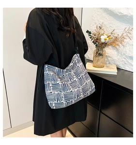Vue détaillée de la bandoulière noire et du motif rayé bleu sur le sac cabas en toile