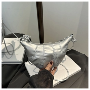 Detail of silver crescent crossbody bag with quilted texture and knotted strap detail