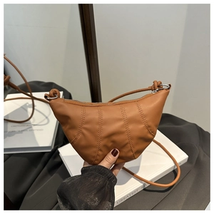 Detail showing vertical stitching and smooth brown PU leather on a croissant bag