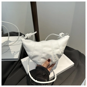 Detail of white quilted crescent bag showing vertical stitching and soft faux leather texture
