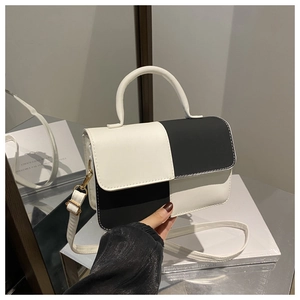 Detail of black and white contrast flap bag with golden hardware and round top handle