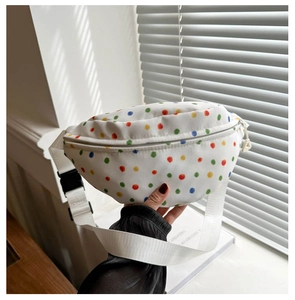 Close-up of canvas waist bag with colorful polka dots, white zipper and nylon strap