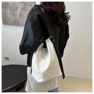 Detail der weißen Canvas-Beuteltasche mit verstellbarem schwarzem Leder-Schultergurt