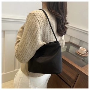 Detail showing embroidered AMELI text on black nylon underarm bucket shoulder bag